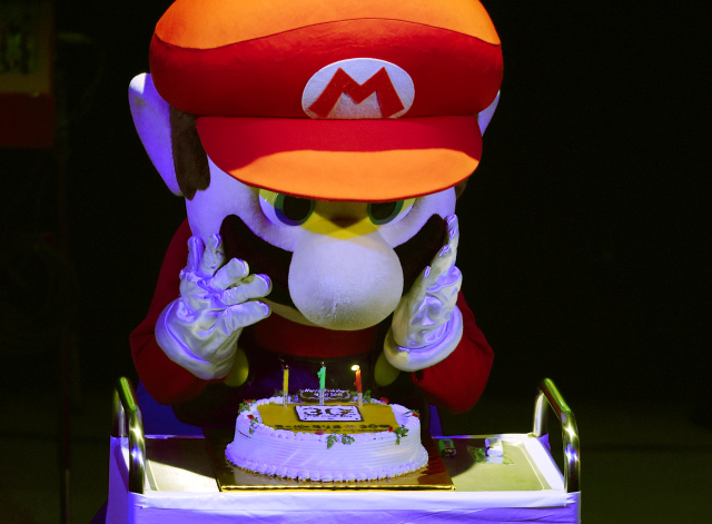 "Super Mario" blows out the candles on a cake during celebrations and a live performance of the most well-known Mario music to mark the game's 30th anniversary in Tokyo on September 13, 2015. Nintendo celebrated the 30th anniversary of Super Mario, one of the best-known characters in video game history, at the event in Tokyo where artists played his theme music to fans dressed up as the hyperactive plumber. AFP PHOTO / TOSHIFUMI KITAMURA