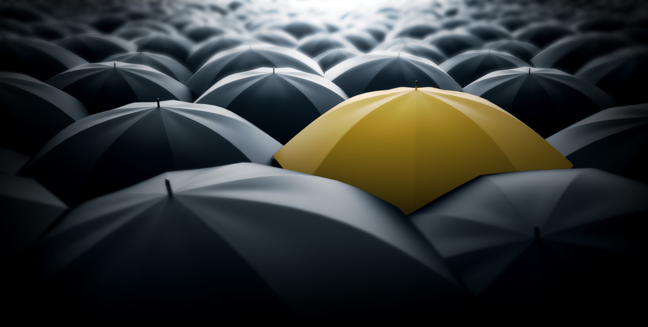 Yellow umbrella in the middle of a sea of black umbrellas, representing special element, a different view in the society.