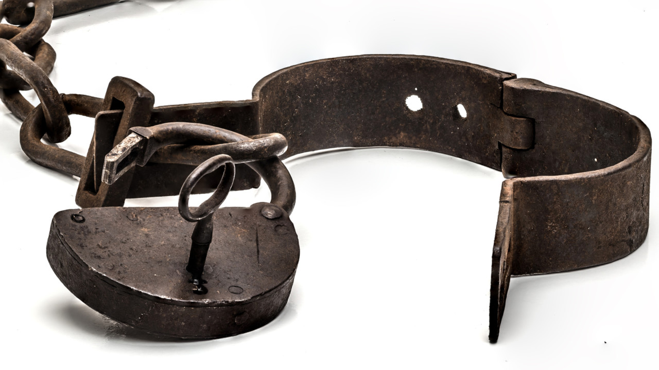 Rusty old shackles with padlock, key and open handcuff used for locking up prisoners or slaves between 1600 and 1800.
